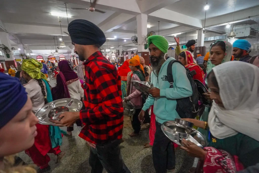 Visitors lining up to eat in one of the large dining halls of the Langar. Famous Food in Amritsar. 