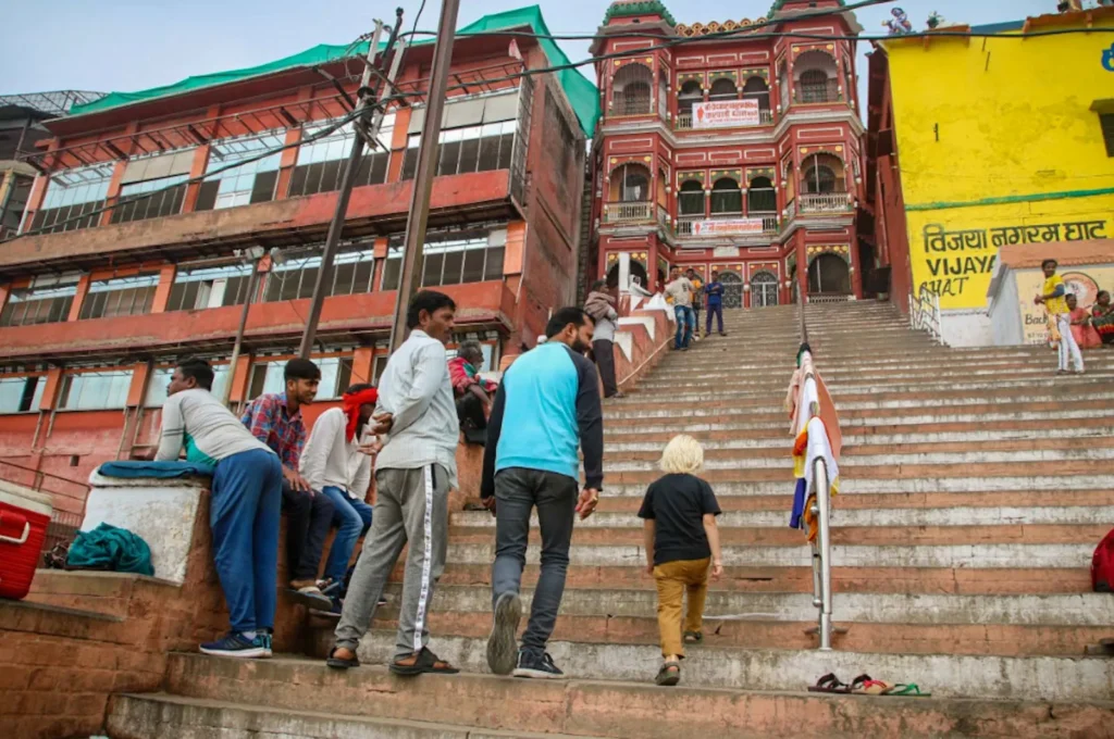 Oscar and Ravi leaving the way uphill from the River Ganges on the stairs of a Ghat in Varanasi with kids. 