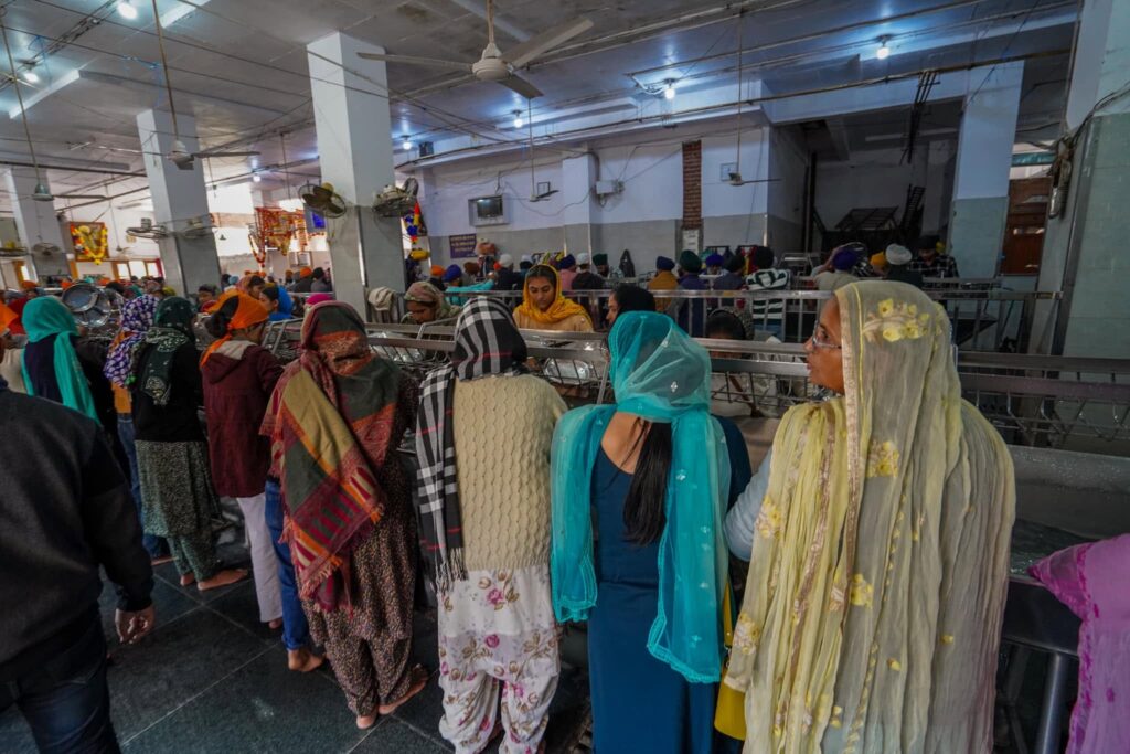 Women washing dishes in the line-up of the dishwashing section of the Langar. 
