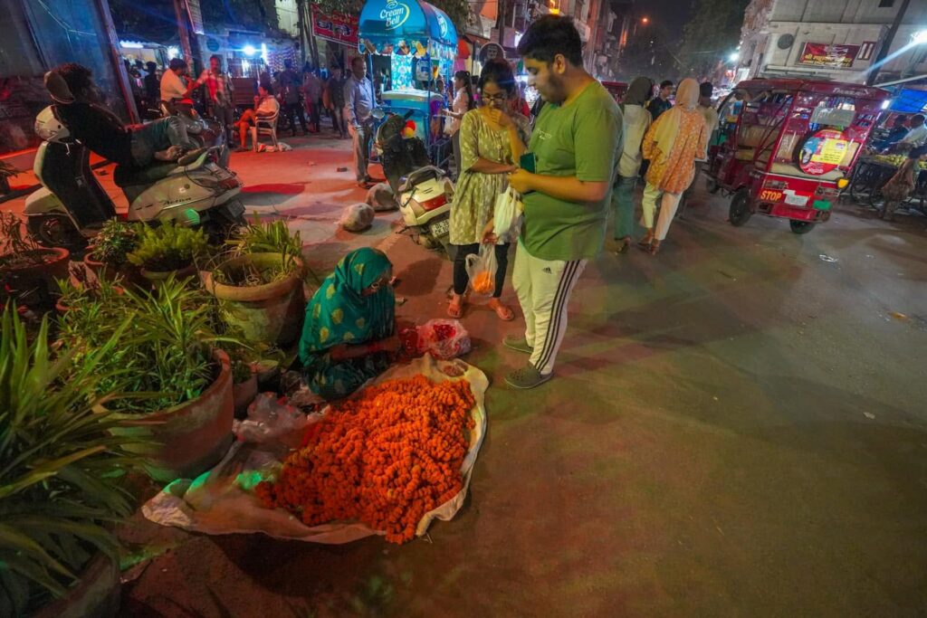 A lady stitching and selling garlands of marigolds. Life lessons learned from travel in India. 